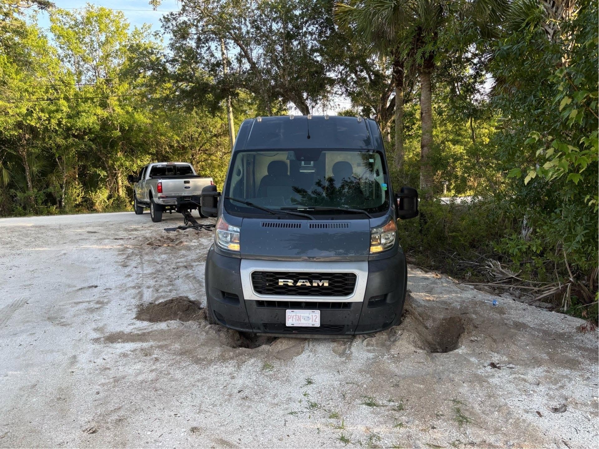 Gray RAM ProMaster van stuck in soft sand with JF Drives recovery truck visible in the background